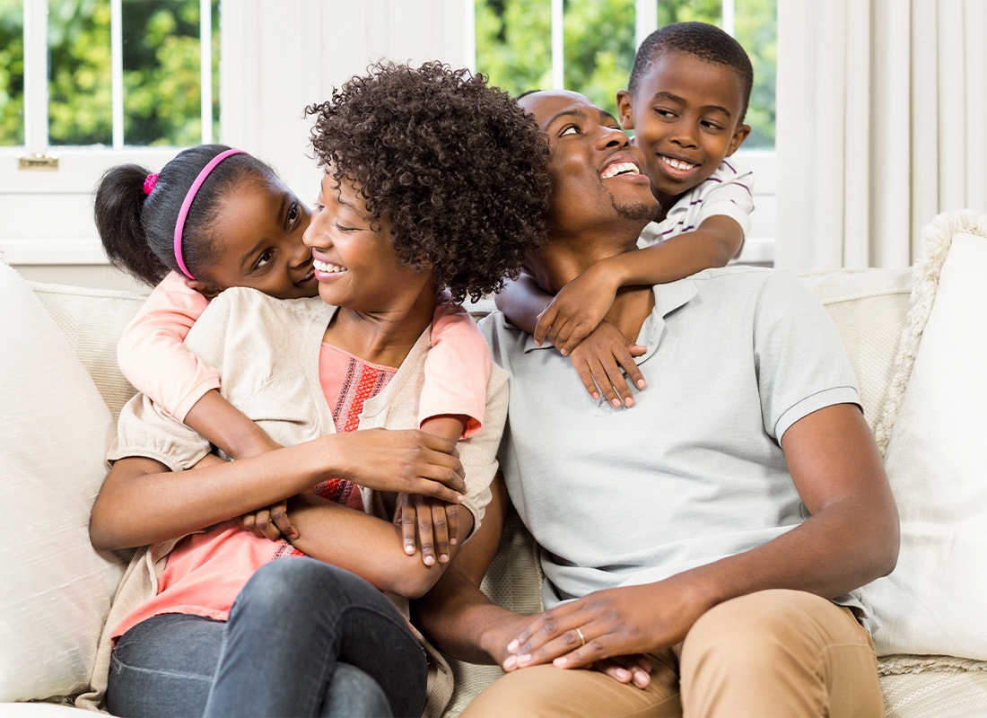 Personal Insurance - Smiling Family Sitting on the Couch Together